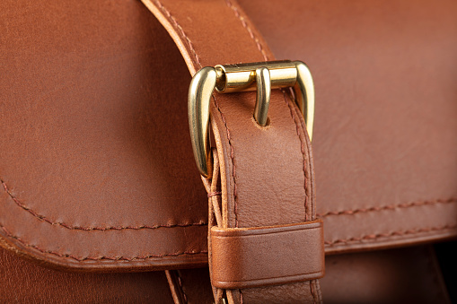 Part of a brown genuine leather bag with a metal latch.