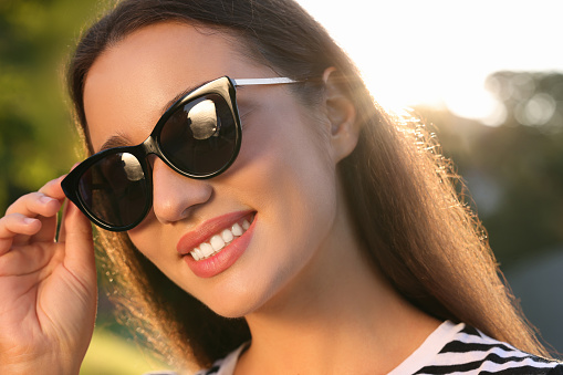 Beautiful smiling woman in sunglasses outdoors on sunny day