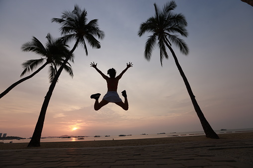 An amazing healthy and joyful woman jumped up from coconut trees on the  beach