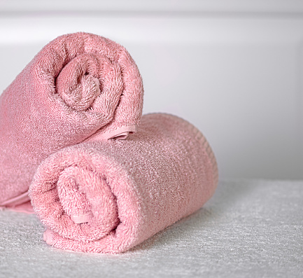 Two pink towels rolled up in the bathroom