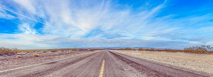 Panoramic picture of a lonely road through mountainous desert during the day