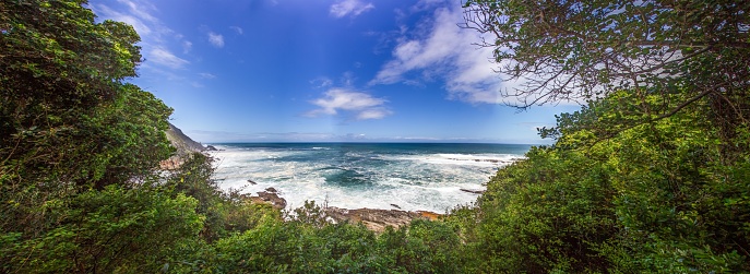 Panoramic view from a forest onto the coast of the Indian Ocean in South Africa's Tsitsikama National Park during the day