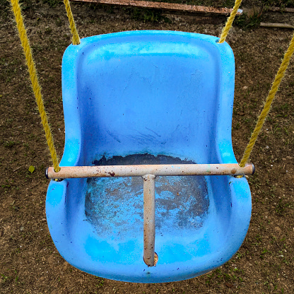 Close up view of empty blue plastic baby swing chair of a residential building in Caracas city