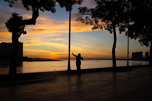 A person relaxes by the riverfront during a beautiful evening sunset in the capital city of Phnom Penh, Cambodia