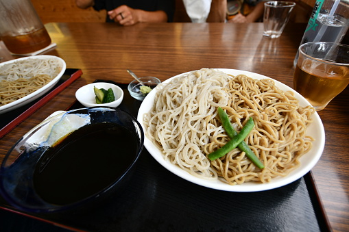 A person is seated at a table, with a pair of bowls filled with delicious looking noodles in front of them