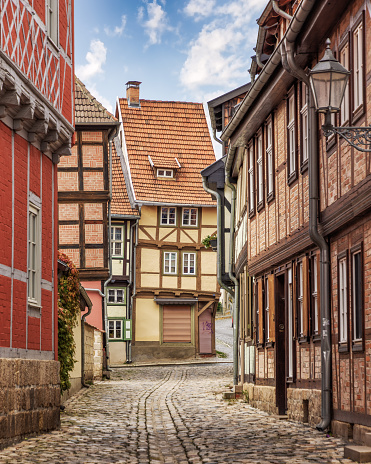 Quedlinburg, Germany – October 31, 2023: This stock photo features a picturesque European street with cobbled stones paving the way to a row of traditional, old-style buildings