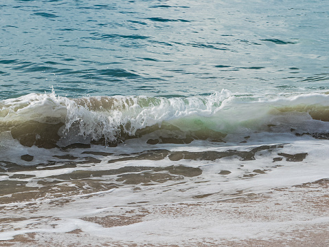 Close up view of a small wave breaking near shore at a sandy California beach