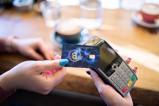 Unrecognizable customer paying with bitcoin card at a cafe.