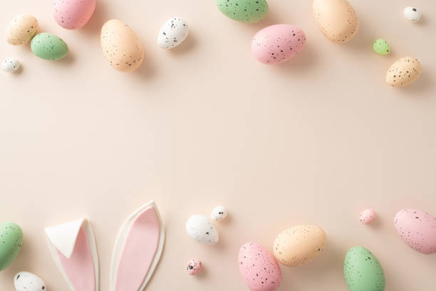 istock Embrace Easter spirit with this charming setup. Top-view shot featuring traditional eggs, playful bunny ears on a pastel beige background. Customizable space for your text or advert 1922567155