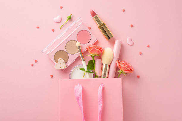 Romantic Valentine's Day shopping. Top view of gift bag brimming with surprises like lipstick, cosmetic brushes, eyeshadow, sprinkles, and roses on soft pink backdrop. Adaptable for love-themed promo compras románticas de san valentín. vista superior de la bolsa de regalo repleta de sorpresas como lápiz labial, pinceles cosméticos, sombra de ojos, chispas y rosas sobre un fondo rosa suave. adaptable para promociones con temática de amor
