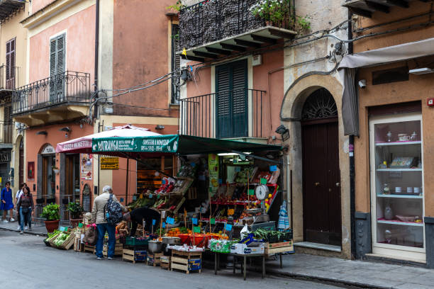 Monreale, Italy - May 12, 2023: Fruit and vegetables store on a street with people around in the old town of Monreale, Palermo, Sicily; Italy;
