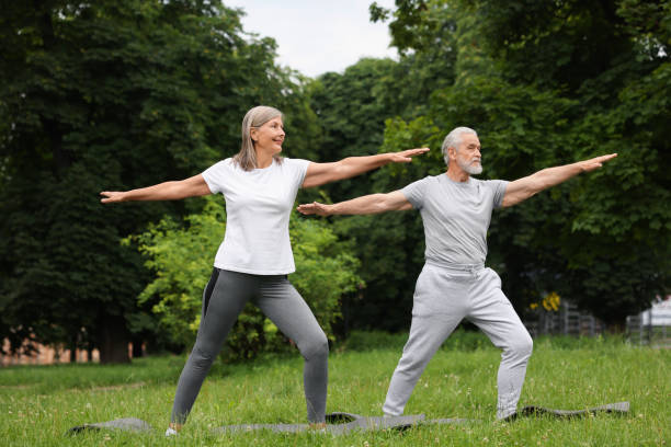 istock Senior couple practicing yoga on green grass in park 1922598659