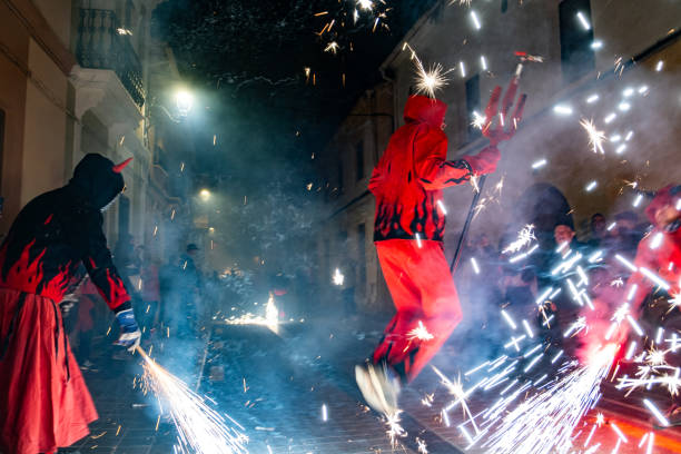 Barcelona, Spain - 09/21/2024 Celebration of the autumn equinox or end of summer, Correfoc.\nPeople celebrating a lively night festival with bright fireworks illuminating the sky and participants in colorful costumes in Carrer de Gracia.
