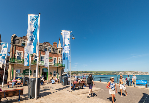 Swanage, UK. 4 September 2023. Various flags on the promenade in Swanage and tourists walking around.