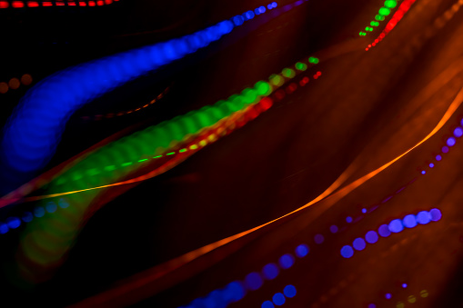 Fiber optics light trails abstract background. Glowing defocused lights and lines on a dark background