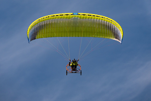 parasail with two swimmers hanging  being pulled by a motor boat