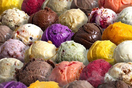 Colorful ice cream scoops in paper cups with berries on wooden table