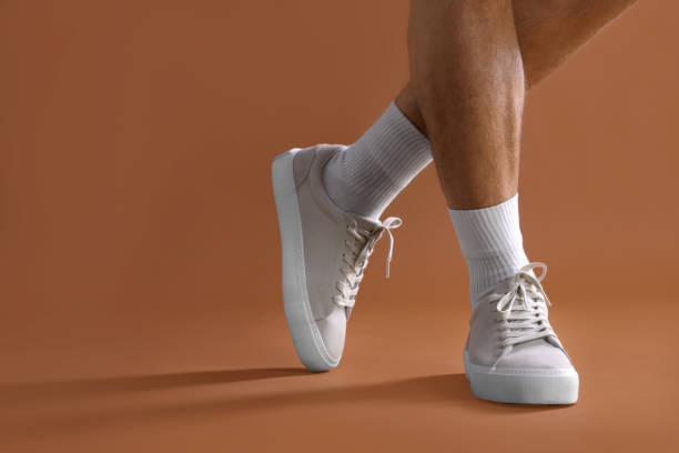istock Man wearing stylish sneakers on brown background, closeup. Space for text 1922627735