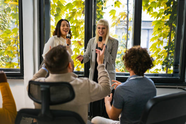 istock Business people making team training exercise during team building seminar singing karaoke 1922628781