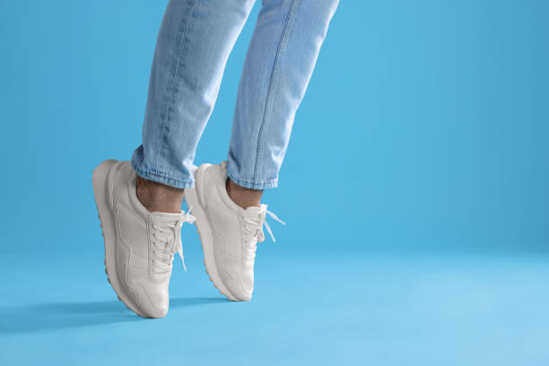 istock Man wearing stylish sneakers on light blue background, closeup. Space for text 1922631451