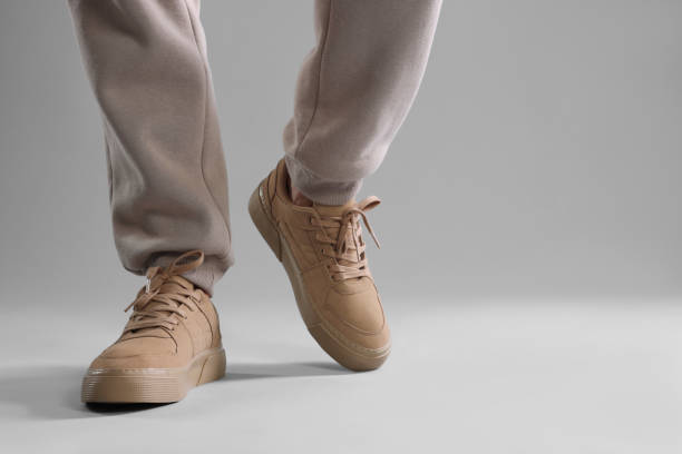 istock Man walking in sneakers on light grey background, closeup. Space for text 1922631455