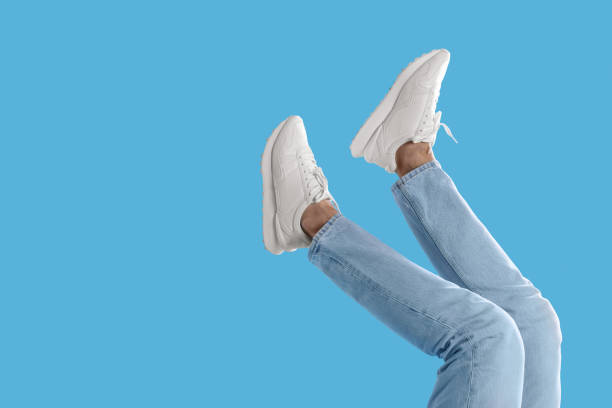 istock Man wearing stylish sneakers on light blue background, closeup. Space for text 1922631502