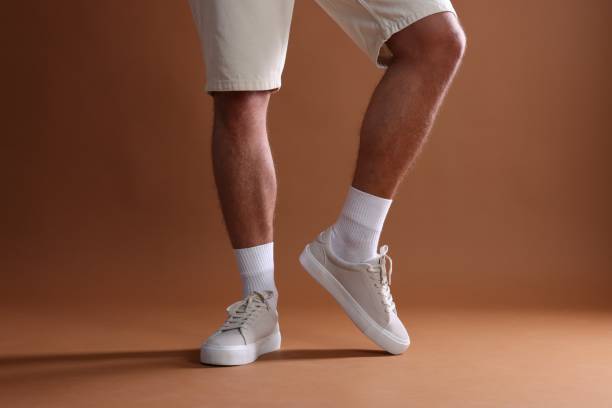istock Man wearing stylish sneakers on brown background, closeup 1922632533