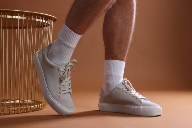 istock Man wearing stylish sneakers on brown background, closeup 1922632536