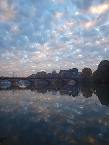 Sunrise at Po river, with multicolor clouds reflectingin the water