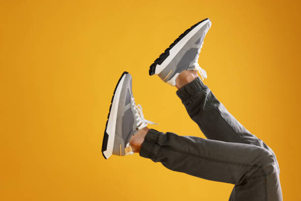 istock Man wearing stylish sneakers on yellow background, closeup. Space for text 1922634687
