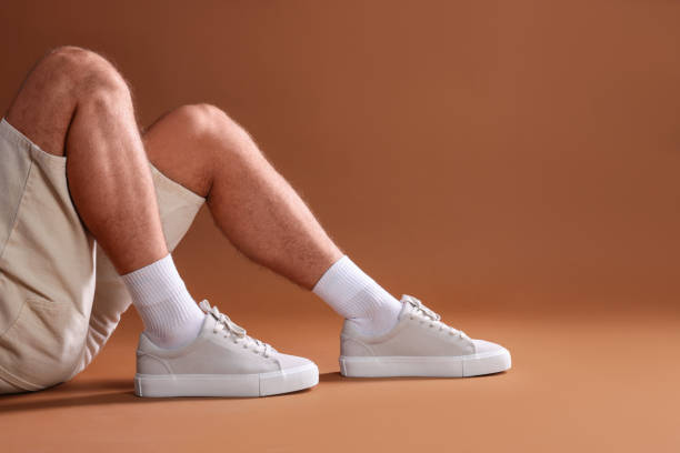 istock Man wearing stylish sneakers on brown background, closeup. Space for text 1922636322