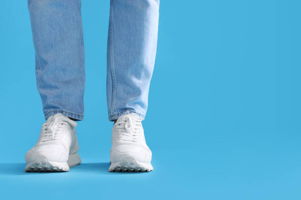istock Man wearing stylish sneakers on light blue background, closeup. Space for text 1922636841