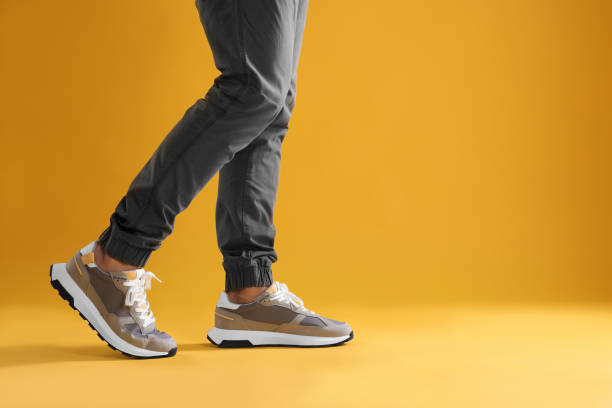 istock Man walking in sneakers on yellow background, closeup. Space for text 1922637390