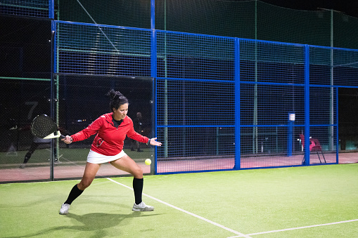 Padel Tennis Player Serving during a match at night