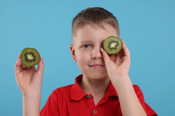 istock Boy with fresh kiwi on light blue background 1922654372