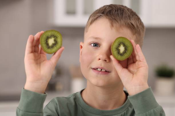 istock Cute boy with fresh kiwi at home 1922654811