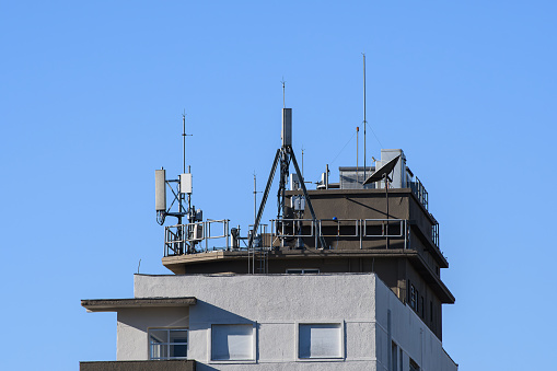 Several signal antennas on top of a tall building.