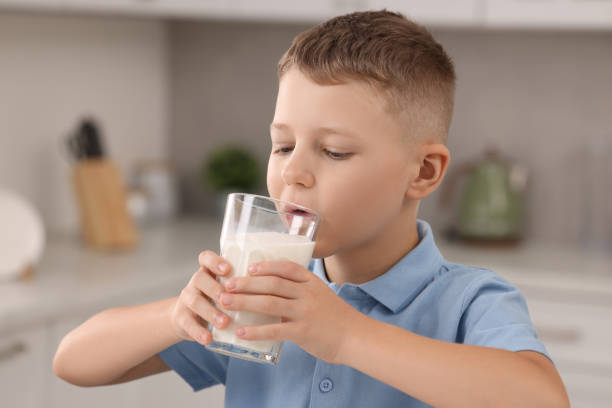 istock Cute boy drinking fresh milk from glass indoors 1922661771