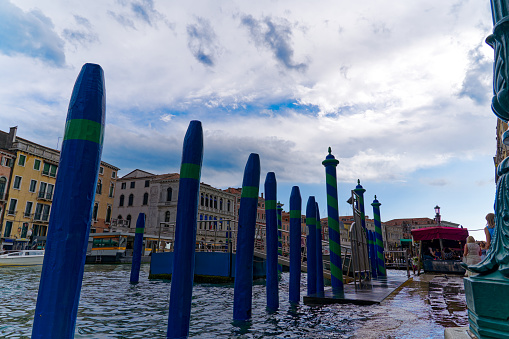 Old town of City of Venice with wooden poles at Grand Canal with Rialto Pier on a blue cloudy summer day. Photo taken August 6th, 2023, Venice, Italy.