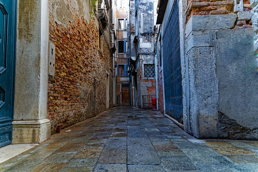 Alley with weathered facades at the old town of Italian City of Venice on a sunny summer day. Photo taken August 6th, 2023, Venice, Italy.