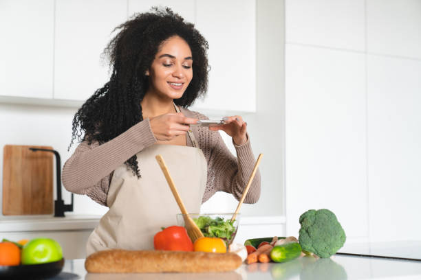 istock Happy african woman taking photo vlogging blogging while cooking 1922710152
