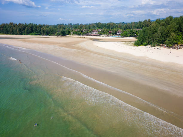istock Large, sandy tropical beach and shallow, warm ocean surrounded by lush, green foliage 1922712954