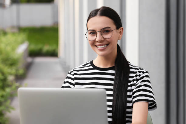 istock Happy young woman using modern laptop outdoors 1922729891
