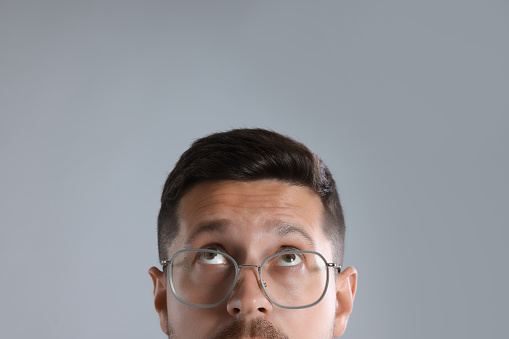 Man in stylish glasses on light grey background, closeup