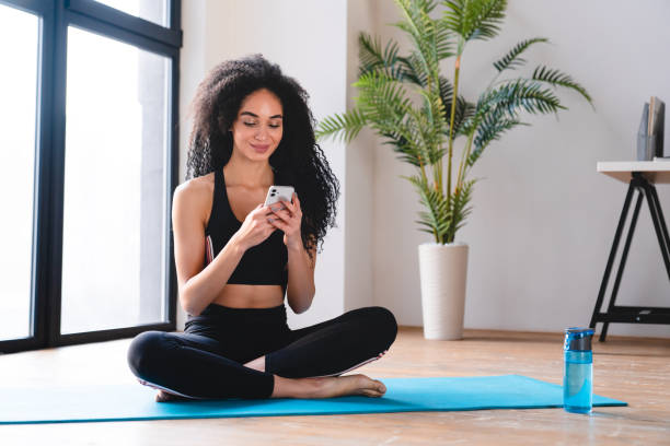 istock Young african female athlete doing workout from home, using smart phone 1922758090