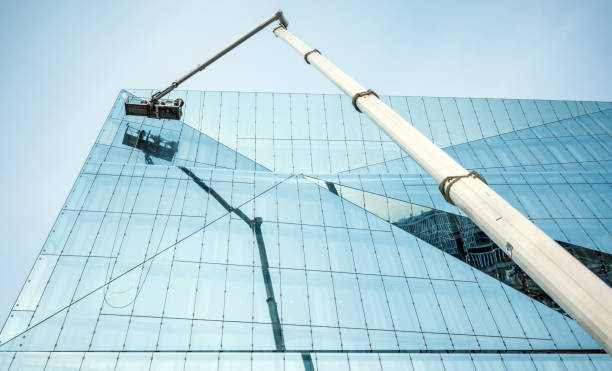 istock Cleaner worker using a cherry picker to clean a glas facade of a contemporary office building 1922764890