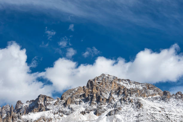 Snow capped mountain peaks of Latemar group in the Dolomites, South Tyrol, Italy. Beautiful blue sky around.