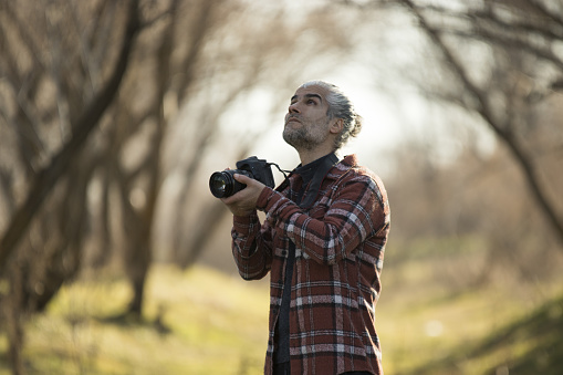 handsome photographer with long hair takes nature photos