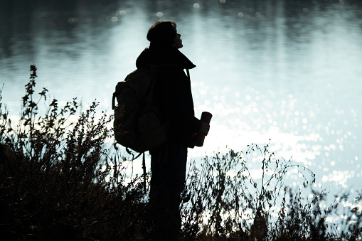 silhouette of lady taking a nature trip by the river at sunset