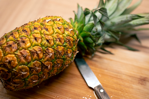 Cutting fresh pineapple on a cutting board in the kitchen.